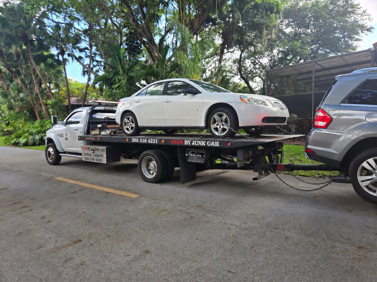 White sedan on a flatbed truck during a residential vehicle pickup