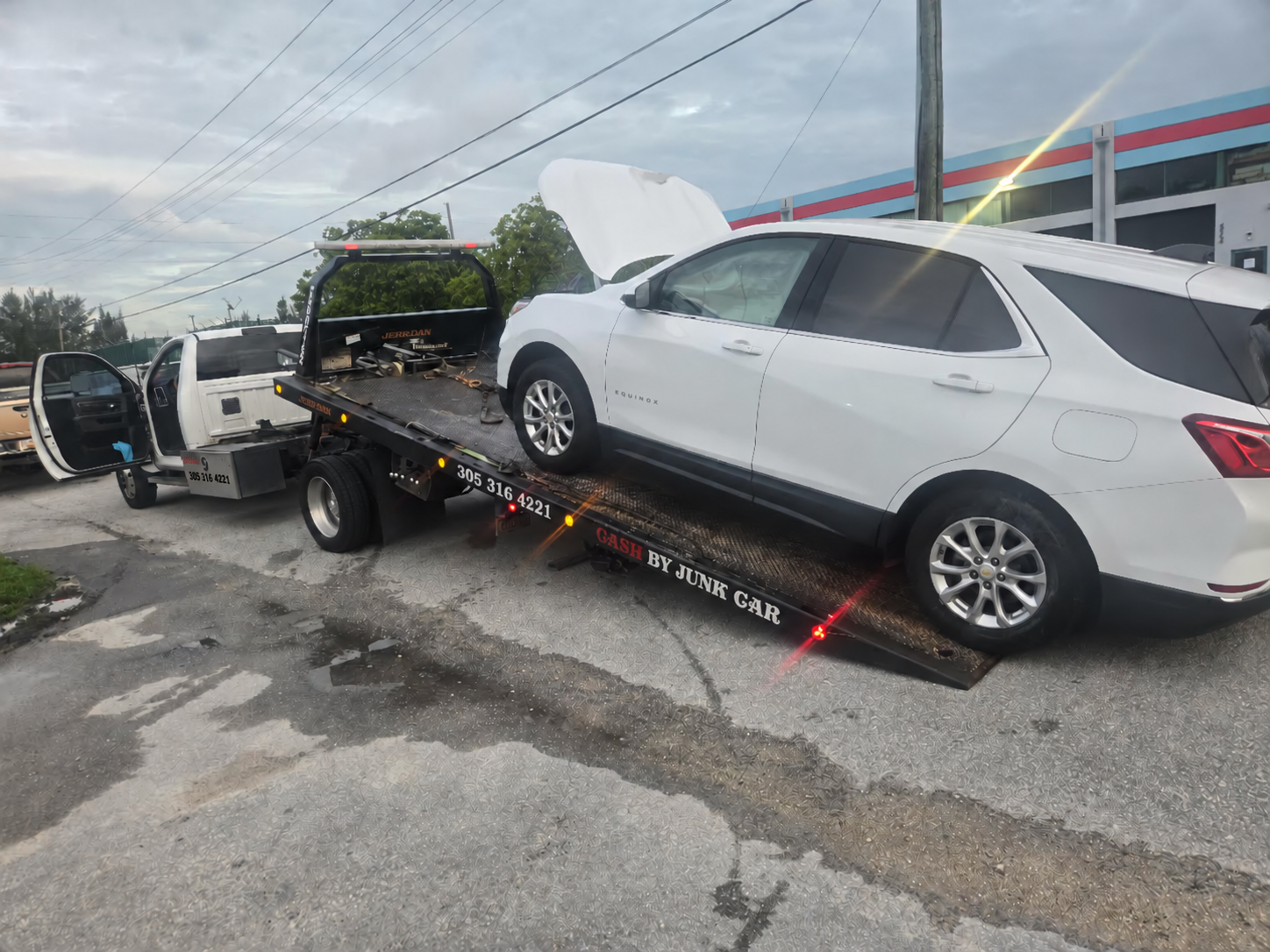 White Chevrolet SUV being loaded onto a flatbed tow truck