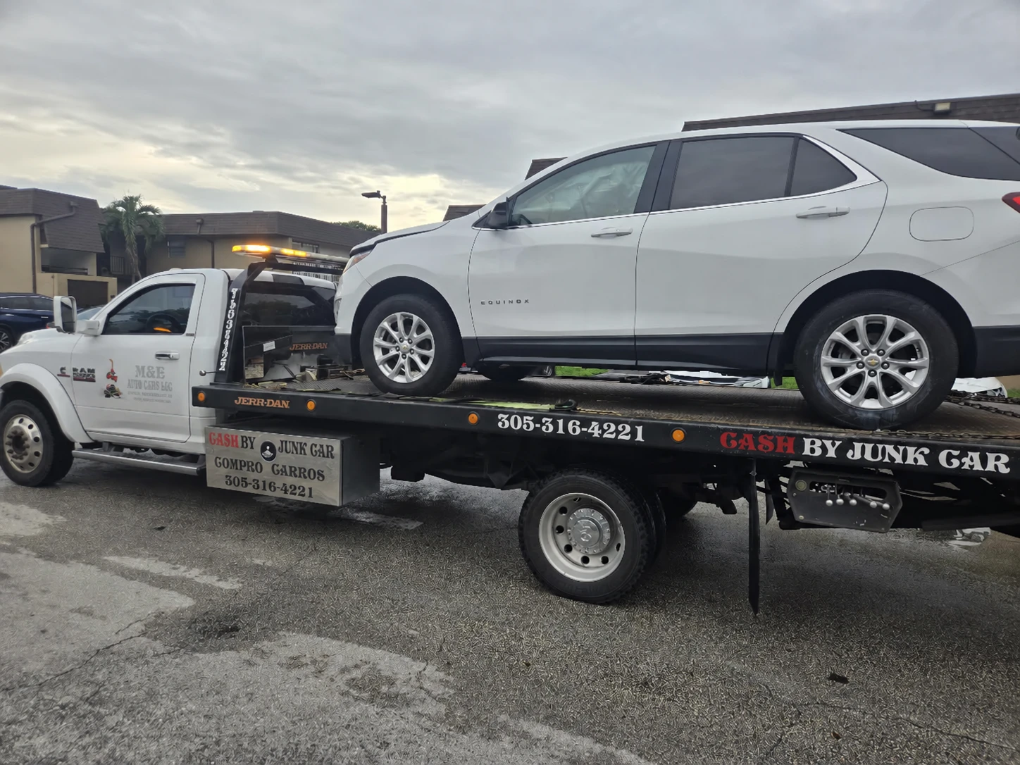 White SUV loaded on a flatbed tow truck displaying 305-316-4221